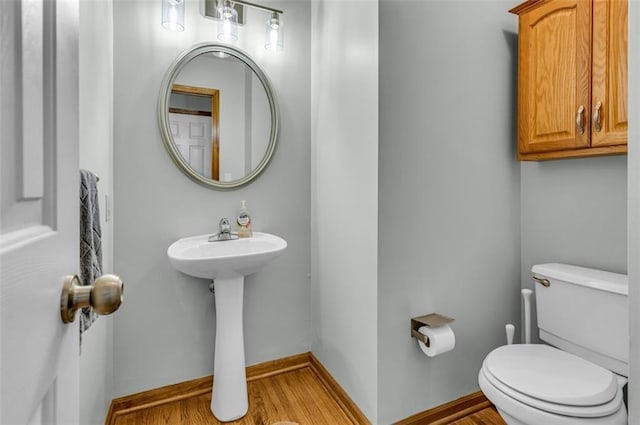 bathroom with toilet, wood-type flooring, and sink