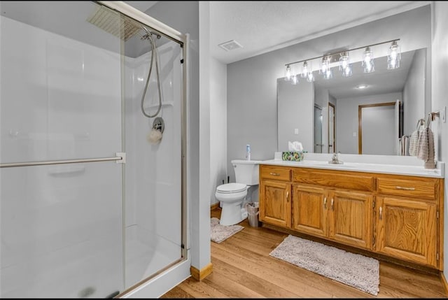 bathroom featuring vanity, hardwood / wood-style flooring, toilet, and a shower with door