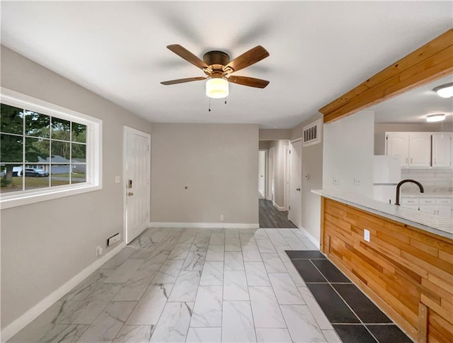 interior space with white cabinets, backsplash, ceiling fan, and white refrigerator