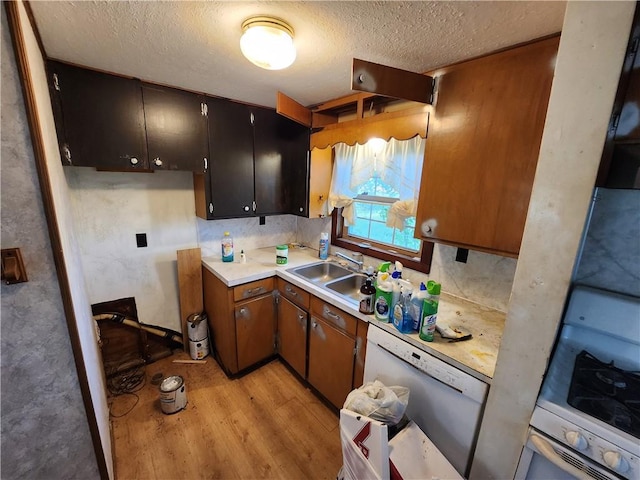 kitchen featuring white appliances, a textured ceiling, light hardwood / wood-style floors, and sink