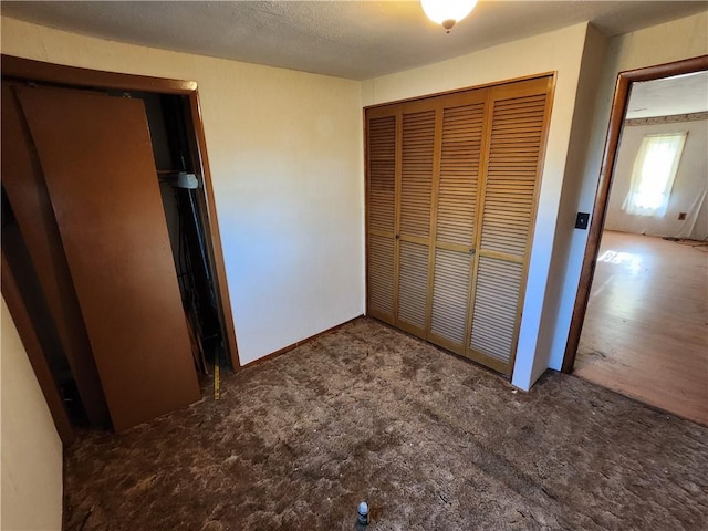 unfurnished bedroom featuring carpet floors, a textured ceiling, and a closet