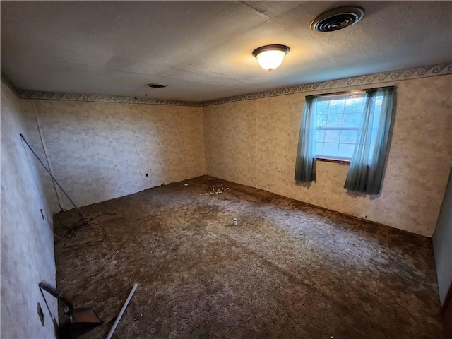 empty room with a textured ceiling and carpet