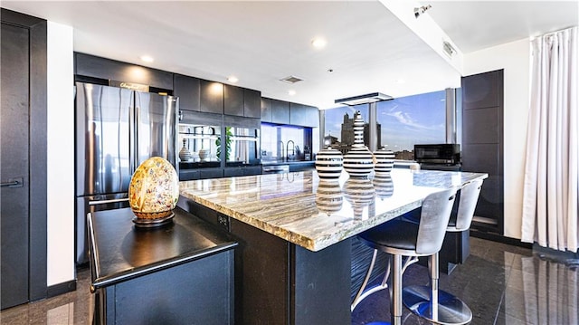 kitchen with granite finish floor, a kitchen breakfast bar, modern cabinets, and freestanding refrigerator