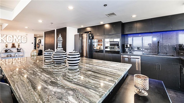 kitchen featuring visible vents, a large island, a sink, stainless steel appliances, and decorative backsplash