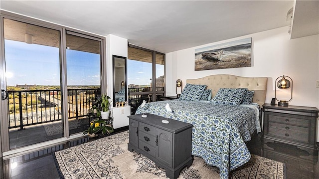 bedroom with expansive windows, wood finished floors, and access to exterior