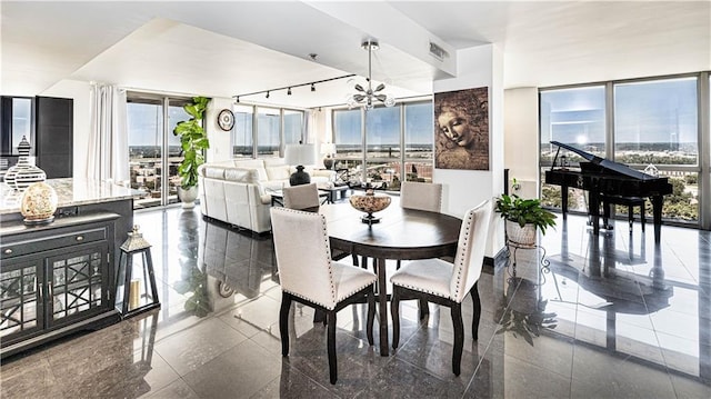 dining area featuring a wall of windows, visible vents, a chandelier, and granite finish floor