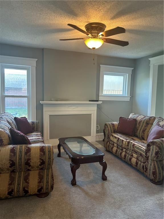 living room with ceiling fan, a textured ceiling, and carpet flooring