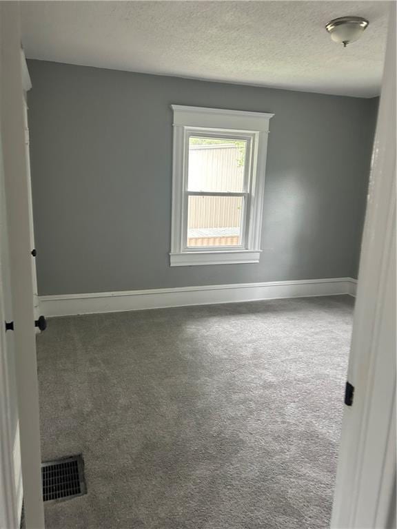 carpeted spare room featuring a textured ceiling