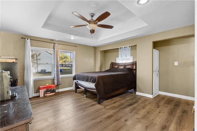 bedroom featuring hardwood / wood-style floors, ceiling fan, and a raised ceiling