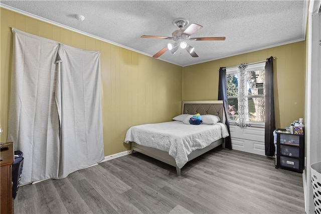 bedroom with a textured ceiling, light hardwood / wood-style flooring, ceiling fan, and crown molding