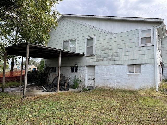 rear view of house featuring a lawn and a carport