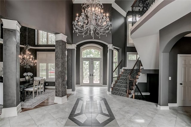 entrance foyer with french doors, light hardwood / wood-style flooring, a towering ceiling, and a chandelier