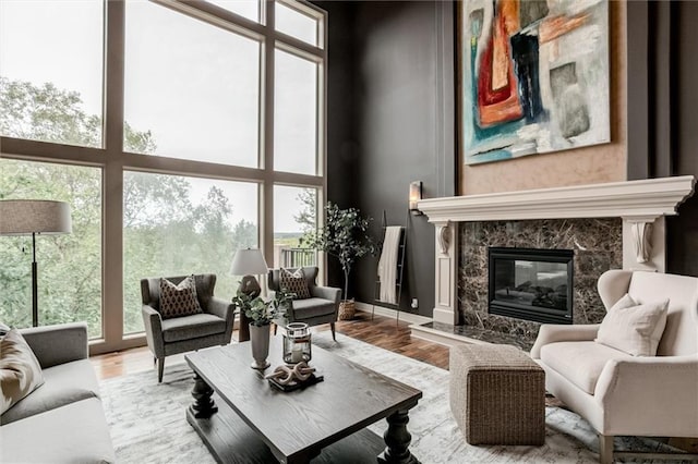 living room featuring light hardwood / wood-style flooring, a wealth of natural light, a premium fireplace, and a high ceiling