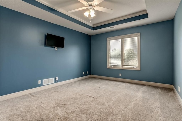 spare room with a raised ceiling, carpet, crown molding, and ceiling fan