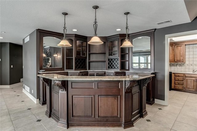 kitchen featuring decorative backsplash, a textured ceiling, a center island, and pendant lighting