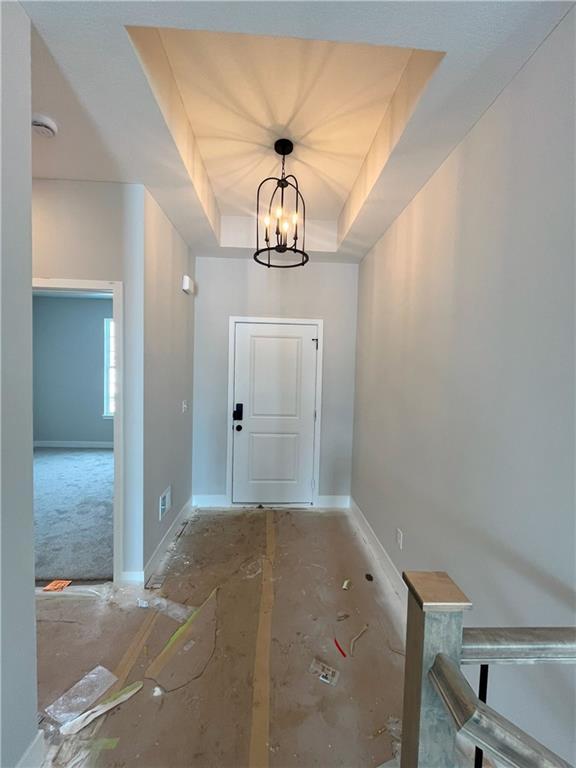 doorway with an inviting chandelier and a tray ceiling