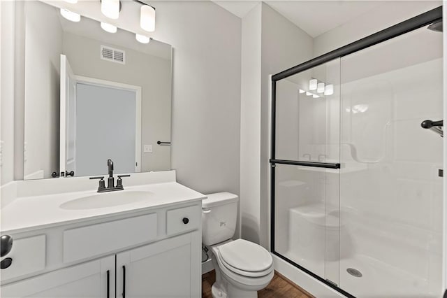 full bathroom with visible vents, toilet, a stall shower, vanity, and wood finished floors