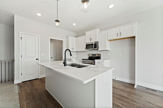 kitchen with stainless steel appliances, a sink, visible vents, white cabinetry, and tasteful backsplash