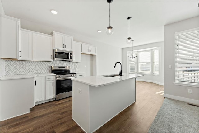 kitchen with dark wood finished floors, stainless steel appliances, decorative backsplash, white cabinetry, and a sink