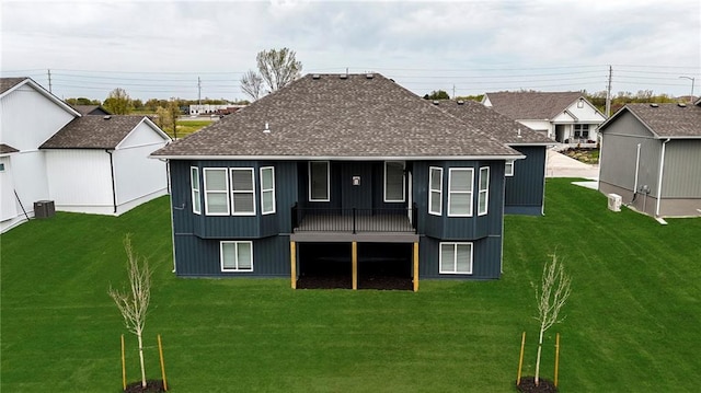 rear view of house with cooling unit, a yard, and a shingled roof