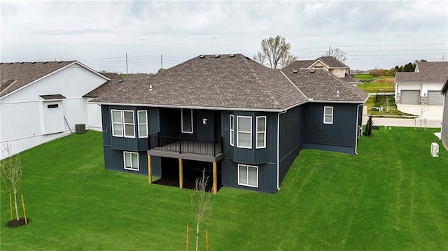 back of property with a lawn, roof with shingles, and cooling unit