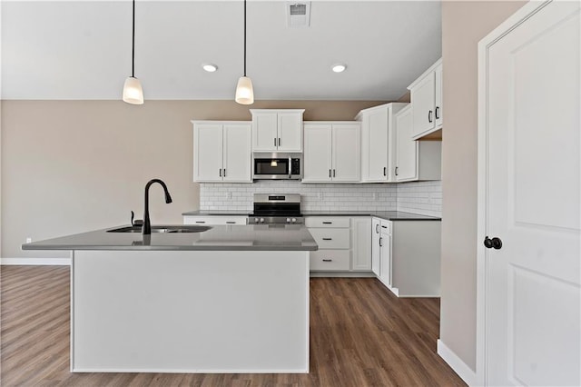 kitchen with stainless steel appliances, a sink, visible vents, tasteful backsplash, and an island with sink