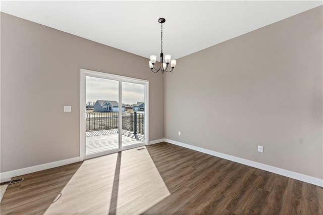 empty room featuring baseboards, wood finished floors, visible vents, and a notable chandelier