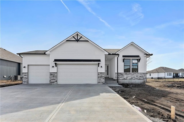 view of front facade with a garage, stone siding, driveway, and central AC unit