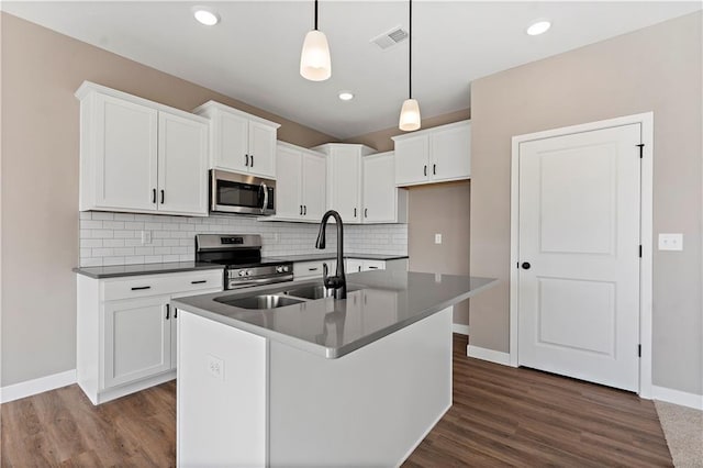 kitchen with appliances with stainless steel finishes, dark wood finished floors, white cabinetry, and tasteful backsplash