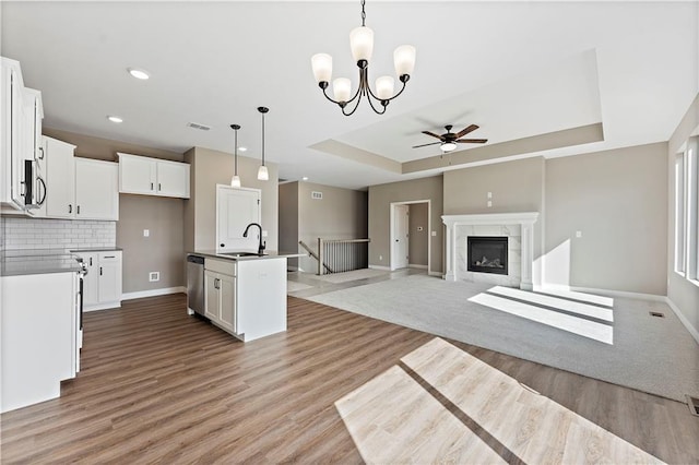 kitchen featuring a raised ceiling, visible vents, light wood-style floors, a sink, and dishwasher