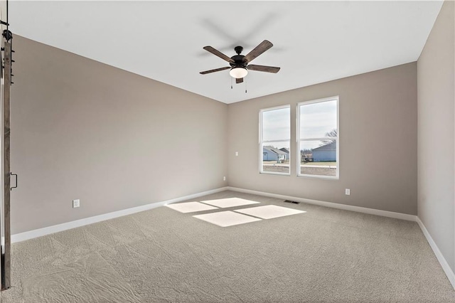 carpeted empty room with a ceiling fan, visible vents, and baseboards