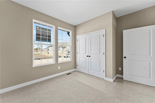 unfurnished bedroom with a closet, light carpet, visible vents, and baseboards