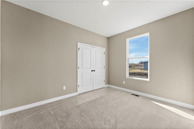 unfurnished bedroom with baseboards, a closet, visible vents, and light colored carpet