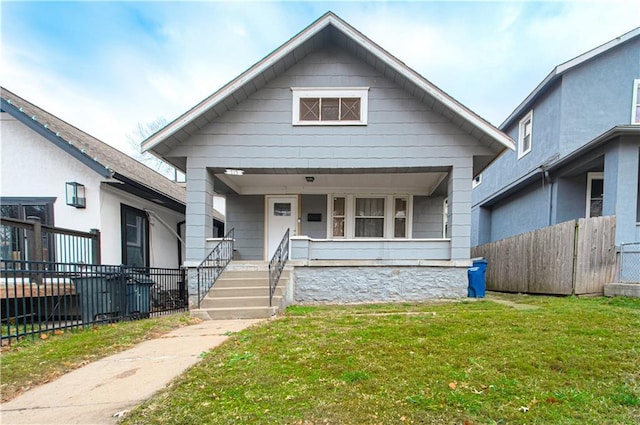 view of front of property with covered porch, fence, and a front yard