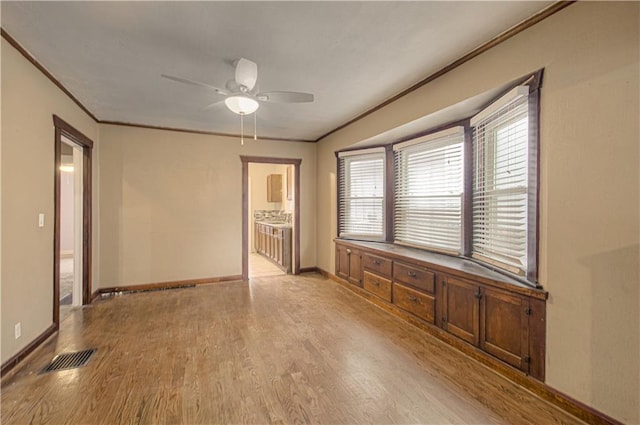 empty room with light wood-style floors, baseboards, and crown molding