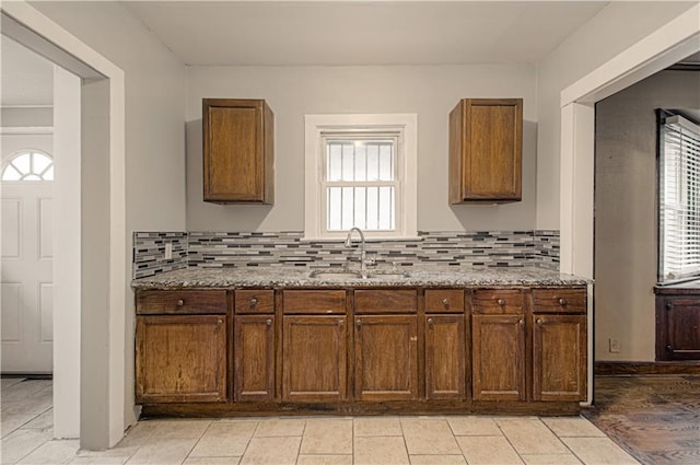 kitchen with light stone counters, backsplash, and a sink