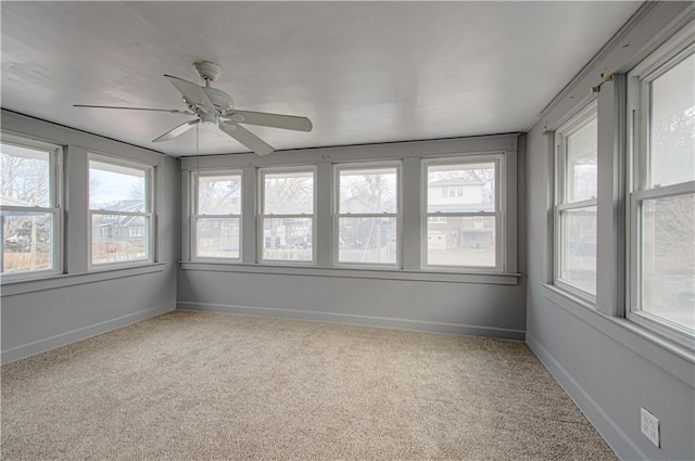 unfurnished sunroom featuring a ceiling fan and plenty of natural light