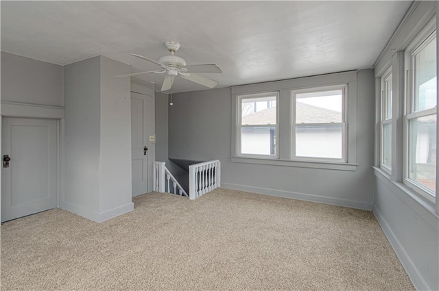 spare room with light colored carpet, ceiling fan, and baseboards