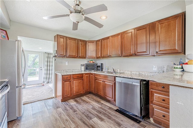 kitchen featuring stainless steel appliances, ceiling fan, light wood-type flooring, and a textured ceiling