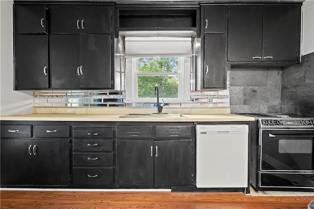 kitchen with decorative backsplash, white dishwasher, sink, and black range oven