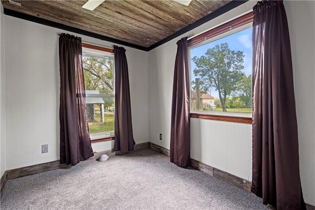 carpeted empty room with crown molding and wooden ceiling