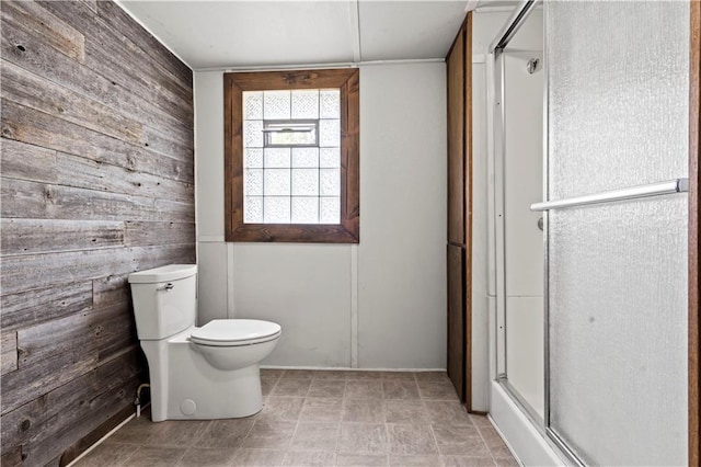 bathroom with toilet, wood walls, and an enclosed shower