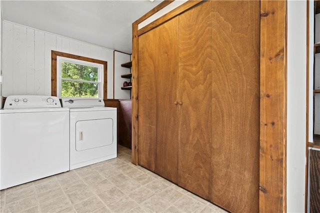 laundry room with separate washer and dryer and wood walls