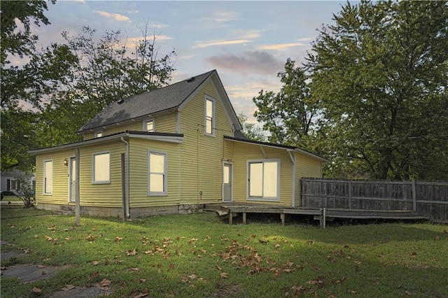 back house at dusk with a lawn