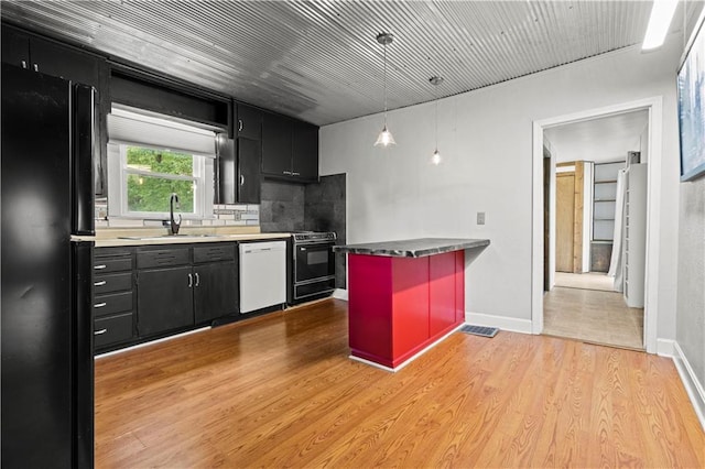 kitchen with sink, dishwasher, light wood-type flooring, and black fridge