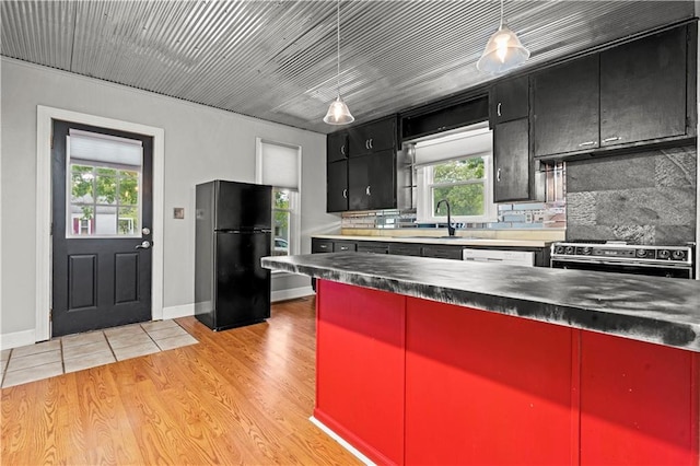 kitchen with backsplash, plenty of natural light, light hardwood / wood-style floors, high end stainless steel range, and black refrigerator