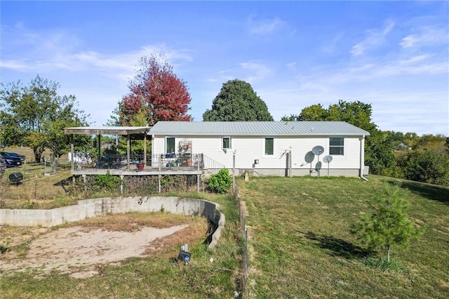 rear view of property featuring metal roof, a wooden deck, and a lawn