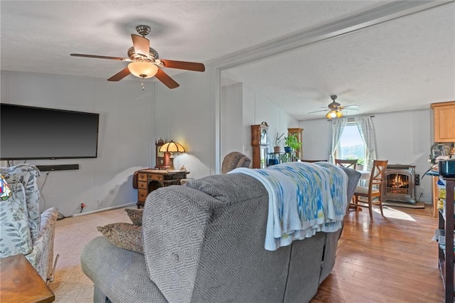 living room featuring ceiling fan, a textured ceiling, and light wood-type flooring