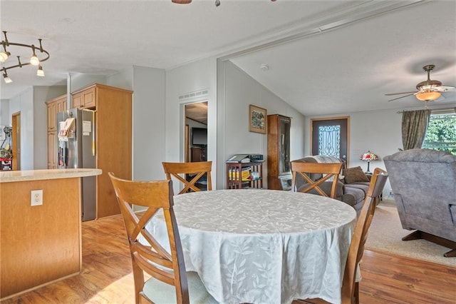 dining space with ceiling fan, vaulted ceiling, and light wood-type flooring