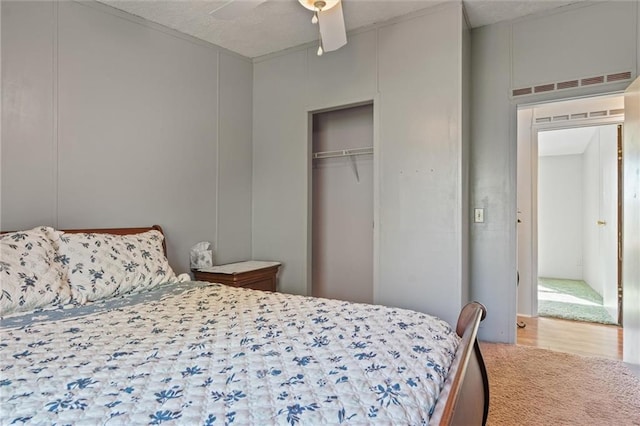 carpeted bedroom with ceiling fan, visible vents, a decorative wall, and a closet